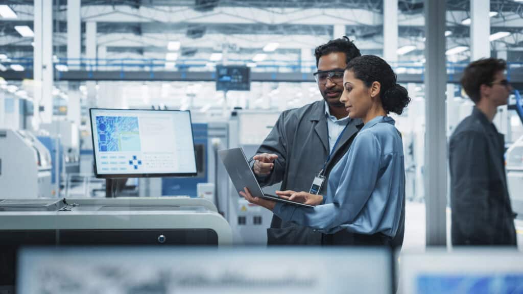 Highly skilled engineers collaborating with digital devices in a modern industrial setting.