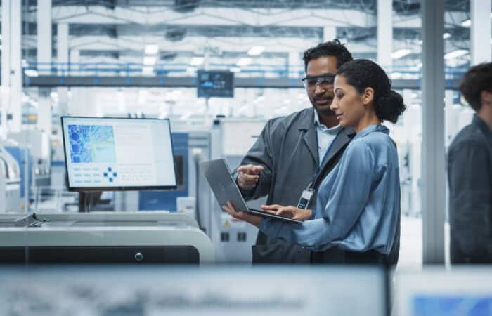 Highly skilled engineers collaborating with digital devices in a modern industrial setting.