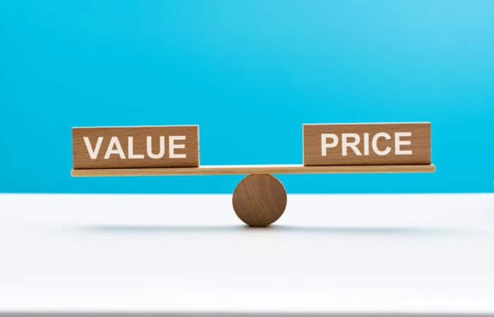 Wooden seesaw with word price and value Balance scale with 'Value' and 'Price' blocks on a blue background.